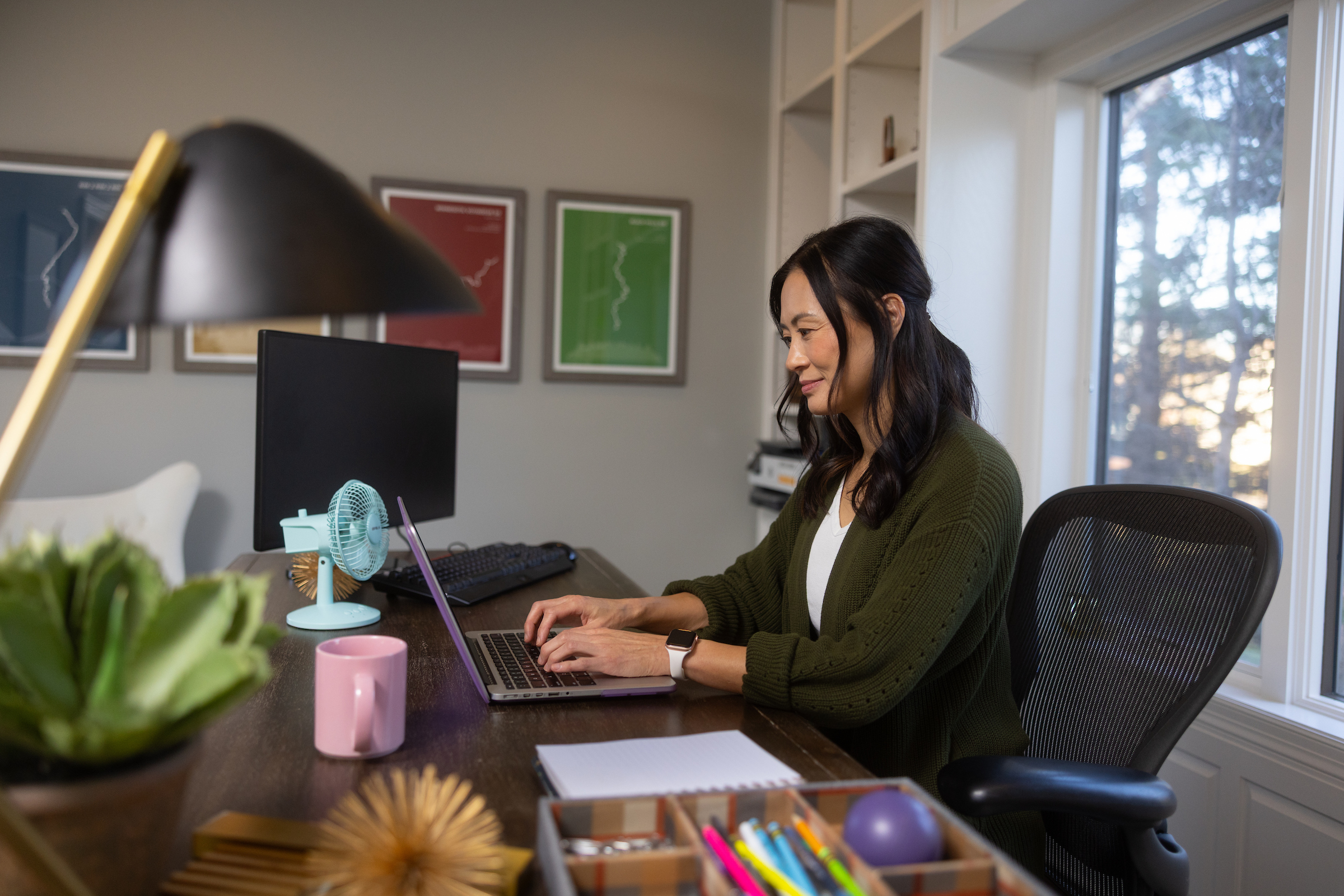 Student sitting in a home working at a desk on a laptop.