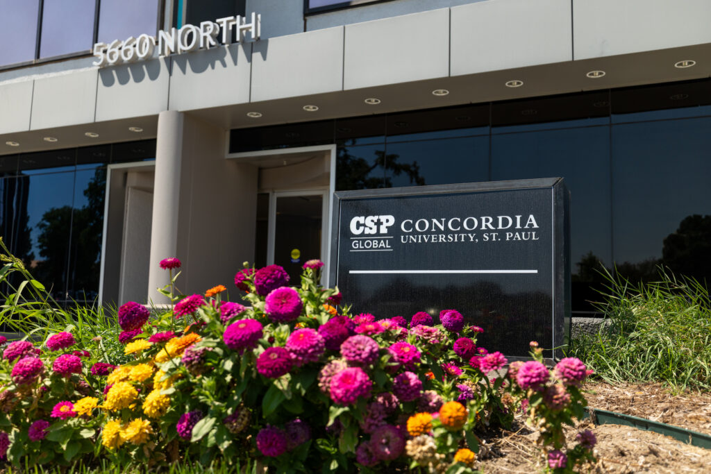 Outside of CSP Global Denver's nursing building with a CSP sign and pink and yellow flowers in front of it.