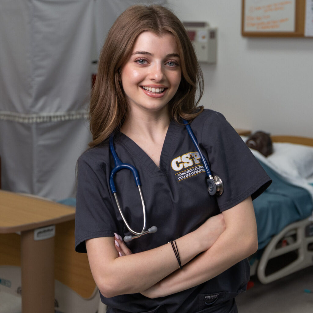 CSP Global nursing student wearing a blue stethoscope standing in a nursing lab setting.
